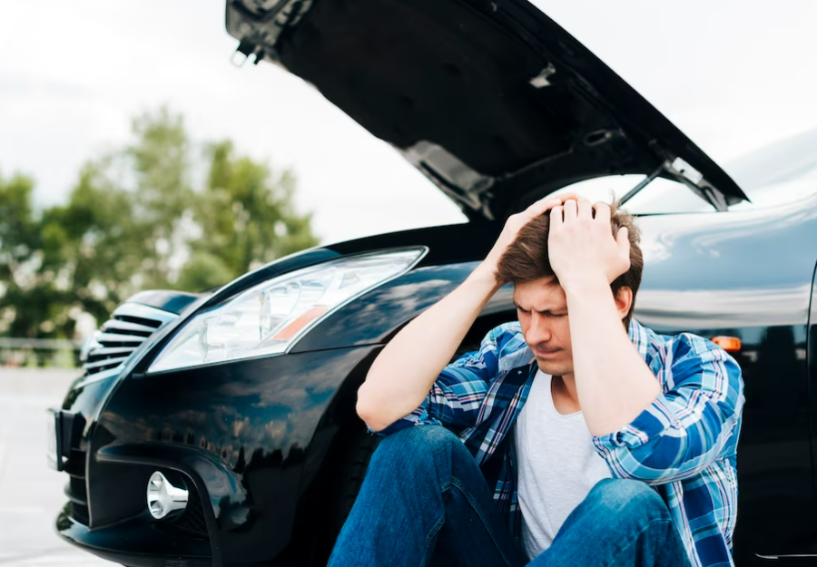 Man sitting next to broken down car
